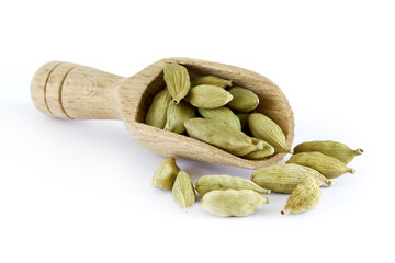 Raw organic green cardamom pods in wooden scoop isolated on white background