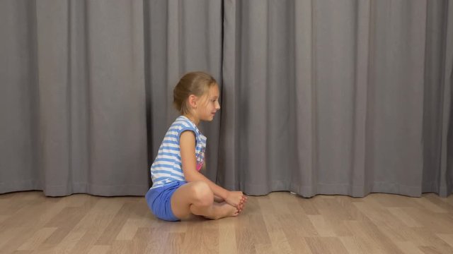 Young girl do yoga butterfly pose. White girl stretchin at living room indoors.