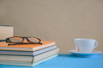 Book glasses and tea on the desk with study and education concept