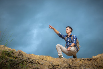 young man on top of the mountain pointing at something