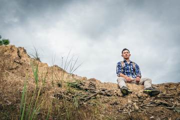 Young man traveller sits on the edge of a cliff.
