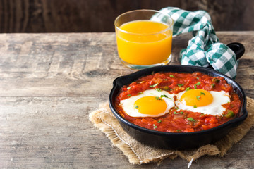 Mexican breakfast: Huevos rancheros in iron frying pan on wooden table