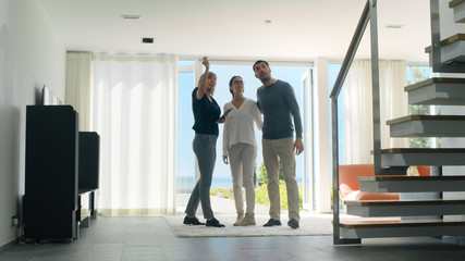 Professional Real Estate Agent Shows Stylish Modern House to a Beautiful Young Couple Who are in...