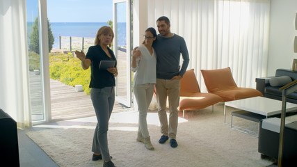 Professional Real Estate Agent Shows Stylish Modern House to a Beautiful Young Couple Who are in...
