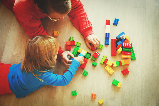teacher and child playing with plastic blocks
