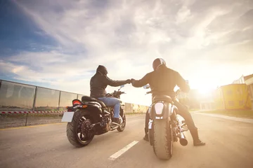 Foto op Plexiglas Two bikers ot motocycles handshaking with knuckle on road at sunshine © kozirsky