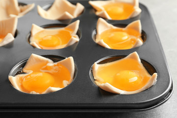 Baking mold with raw eggs in dough, closeup