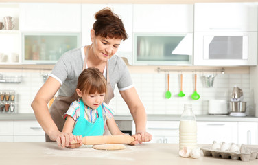 Cute little girl and her grandmother on kitchen