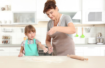 Cute little girl and her grandmother on kitchen