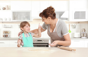 Cute little girl and her grandmother on kitchen