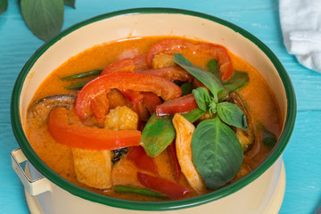 Rotes Thai-Curry in einer Schale auf türkisem Holztisch