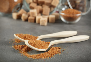 Spoons of brown sugar on grey table