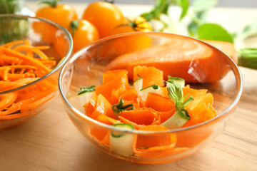 Carrot salad with cucumber in glass bowl on kitchen table