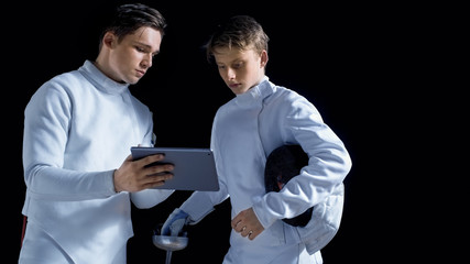Two Young Fully Equipped Fencers Use Tablet Computer To Learn More About Strategy, Attack and...