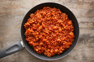 Meat sauce in frying pan on wooden background