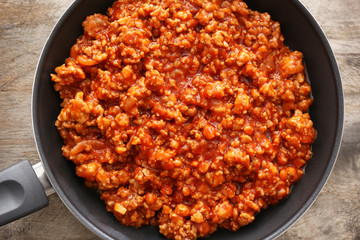 Meat sauce in frying pan on wooden background