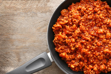 Meat sauce in frying pan on wooden background