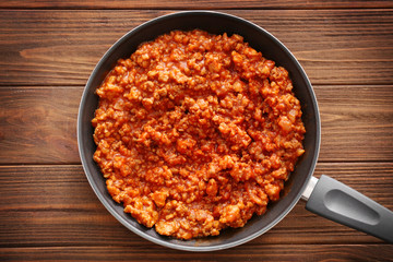 Meat sauce in frying pan on wooden background
