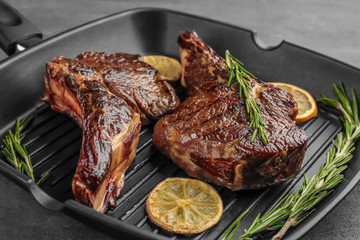 Grill pan with delicious steaks on kitchen table