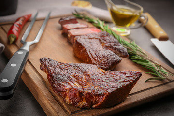 Wooden board with yummy grilled steaks on kitchen table