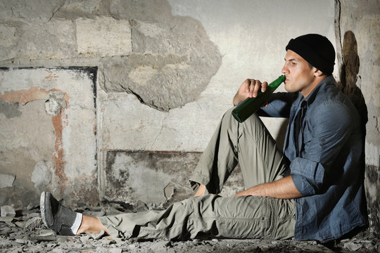 Man sitting and drinking alcohol in abandoned building