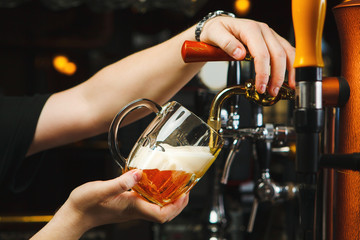 Barman pours beer into a glass goblet from the tap