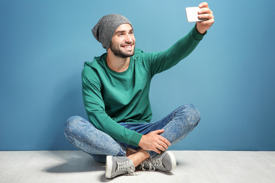 Young man taking selfie against color wall background