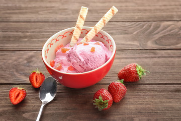 Bowl with delicious strawberry ice-cream on wooden background
