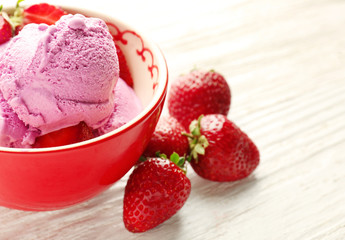 Delicious strawberry ice-cream in bowl on wooden background