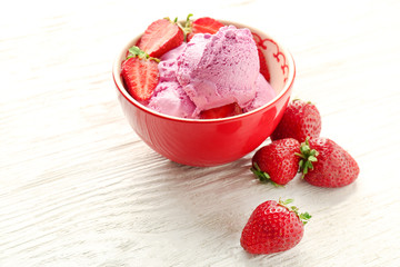 Delicious strawberry ice-cream in bowl on wooden background