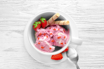 Cup with delicious strawberry ice-cream on wooden background