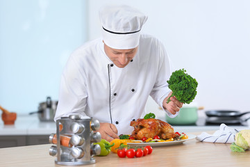 Male chef adding garnish to cooked chicken in kitchen