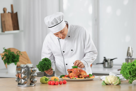 Male chef adding garnish to cooked chicken in kitchen