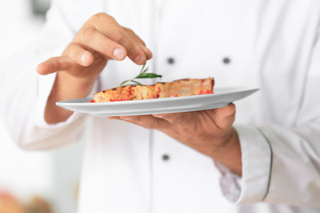 Male chef cooking meat in kitchen, closeup