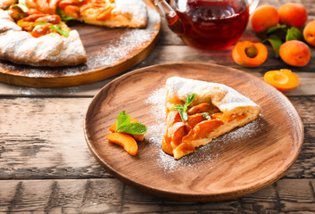 Plate with piece of delicious apricot cake on table