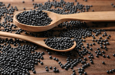 Spoons with healthy lentils on wooden background