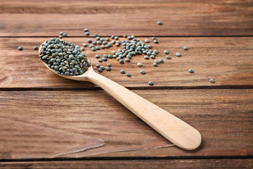 Spoon with healthy lentils on wooden background