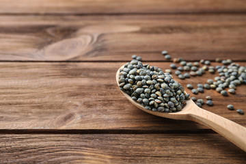 Spoon with healthy lentils on wooden background