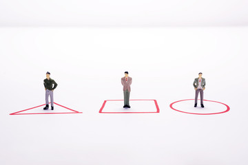 Miniature people three business men standing in red diagrams over white background or backdrop.