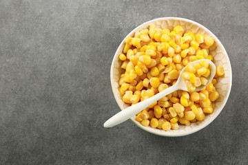 Corn kernels in bowl on grey background