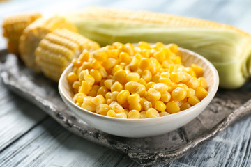 Corn kernels in bowl on wooden background