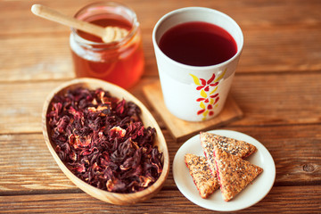 Tea from hibiscus with honey and biscuits on a wooden base