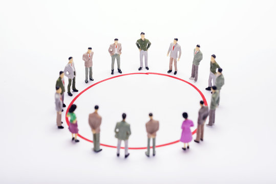 Miniature business people standing in circle over backdrop or background.
