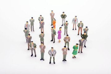 Miniature business people standing in circle over backdrop or background.