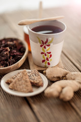 Tea from hibiscus with honey, ginger root and biscuits on a wooden base