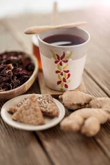 Fotobehang Tea from hibiscus with honey, ginger root and biscuits on a wooden base © BanjaninFoto