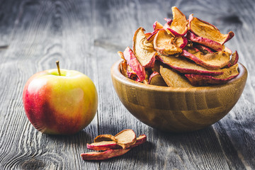 Caramel cinnamon apple chips in wooden bowl. Selective focus, space for text, ton