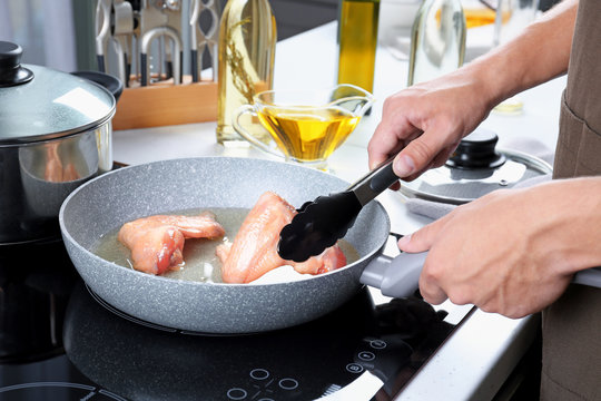 Man cooking chicken wings in frying pan
