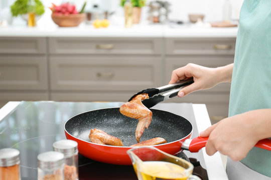 Woman Cooking Chicken Wings In Frying Pan On Stove