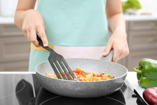 Woman cooking vegetables in frying pan on stove
